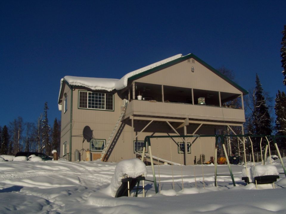 Snow-covered yard with a house and a swing set