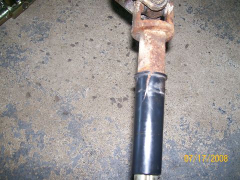 1995 Mercury Grand Marquis - A close-up of a rusted steering shaft component with a black protective boot is shown against a concrete background.