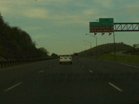 1998 Ford Taurus - A white sedan travels down a highway under an overcast sky, with signs indicating Rocky Gap State Park and Resort.