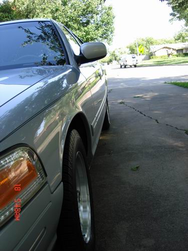 1998 Ford Crown Victoria - A silver 1998 Ford Crown Victoria is seen from the front quarter angle, with a timestamp visible on the headlight.