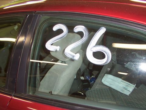 1998 Ford Taurus - White numbers 226 are painted on the side window of a red car, revealing the interior.