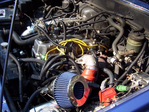 1986 Toyota Hilux - The engine bay of a 1986 Toyota Hilux shows a modified air intake and ignition system.