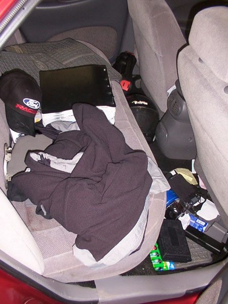 1998 Ford Taurus - Interior view of a car's back seat area, filled with personal belongings and clutter.