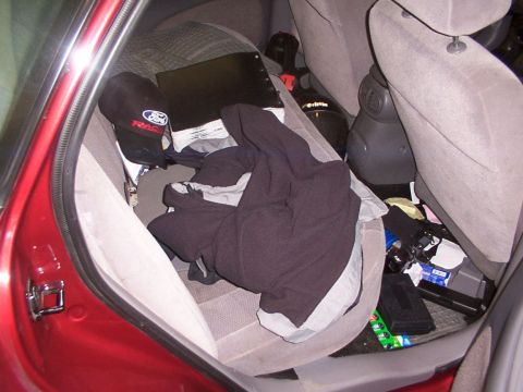 1998 Ford Taurus - The interior of a car is filled with various items, including clothing and a hat with a Ford logo.
