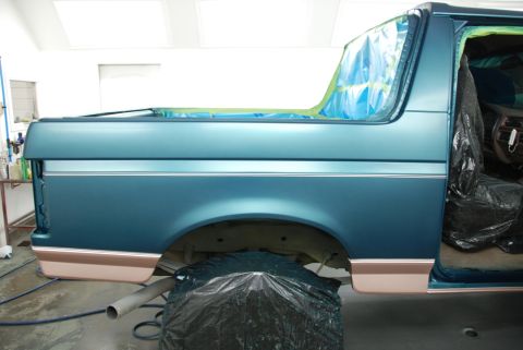 1996 Ford Bronco - The side profile of a 1996 Ford Bronco shows its two-tone paint scheme and chrome trim, with the interior covered for protection.
