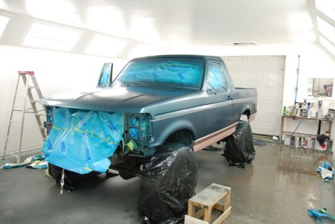 1996 Ford Bronco - A truck is being prepped for a paint job in a workshop, with protective coverings on the front end and windows.