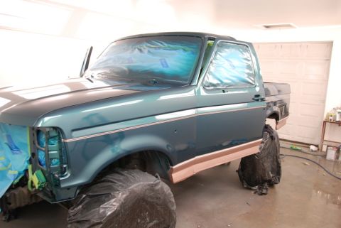 1996 Ford Bronco - A teal Ford truck is being prepped for painting, with its front end and windows covered in protective plastic.