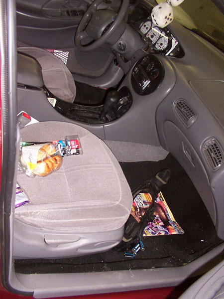 1998 Ford Taurus - The interior of a 1998 Ford Taurus shows a cluttered driver's side with food and magazines.