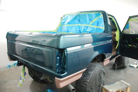 1996 Ford Bronco - A teal Ford pickup truck is being prepped for painting in a workshop, with blue plastic covering the windows and bed.