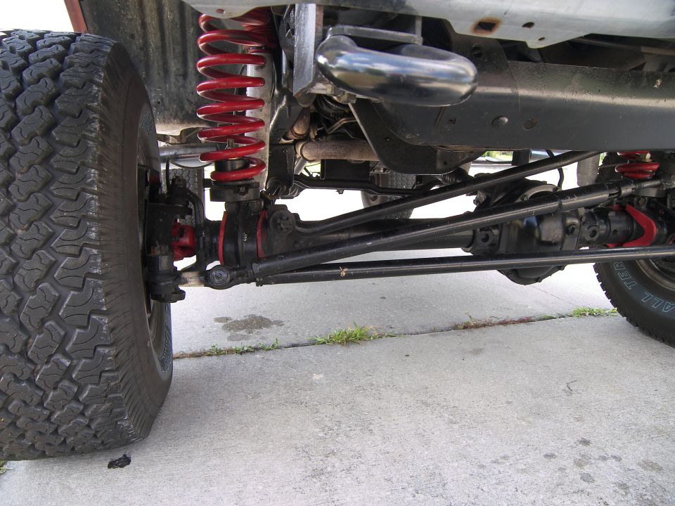 Truck's front suspension with red coil springs and large off-road tire