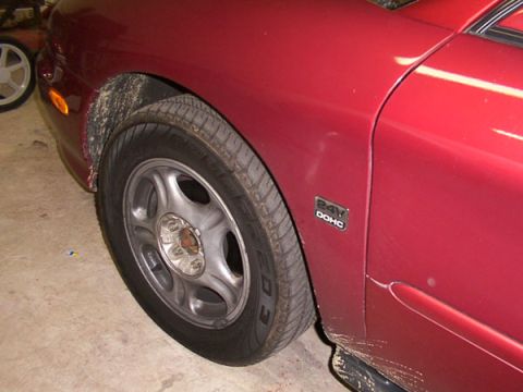 1998 Ford Taurus - Close-up of a red car's fender and wheel, showing a 24V DOHC badge.