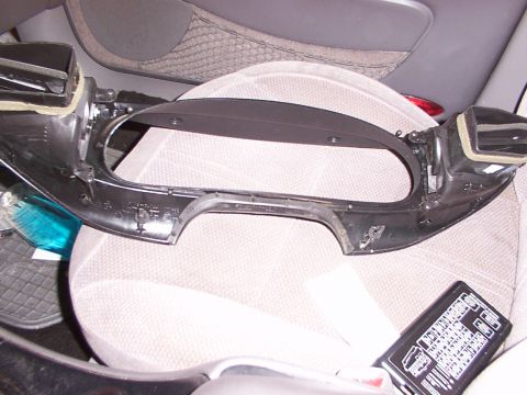 1998 Ford Taurus - A disassembled interior trim piece, likely from a car's dashboard, is shown with air vents and a fuse box visible.