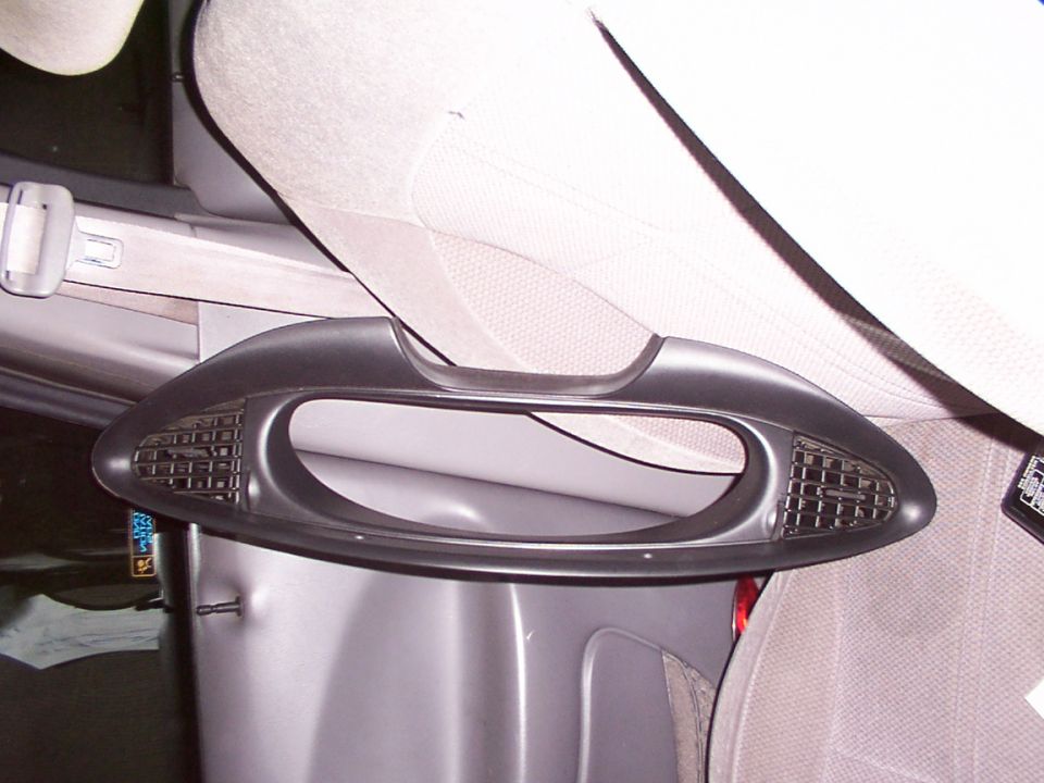 Removed oval dash trim bezel with mesh vents resting on a gray car console