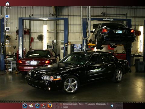 2004 Ford Crown Victoria - Two sedans are parked in a garage, with one on a lift and another in the background.