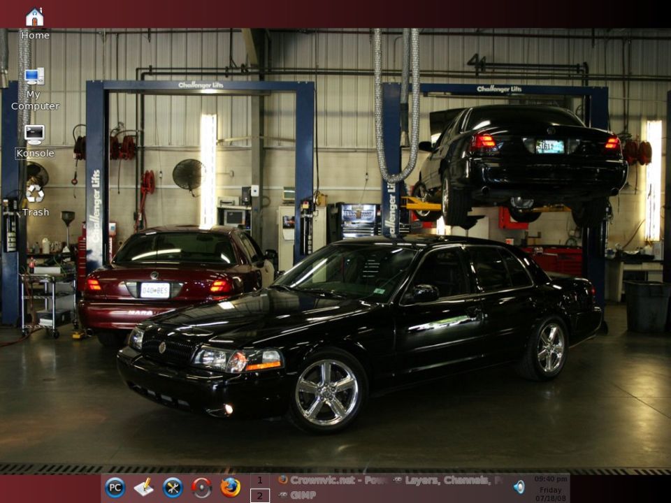 Black sedan in foreground, red sedan behind it, another black sedan on lift in background. Garage setting