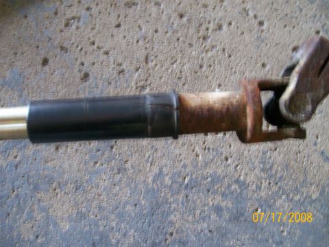 1995 Mercury Grand Marquis - A rusty steering shaft with a u-joint and black protective boot is shown against a concrete background.