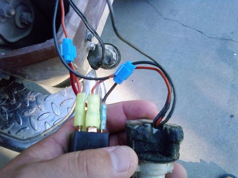 1986 Ford Bronco - Close-up of a hand holding an automotive relay and wiring harness, with visible connectors and wires.