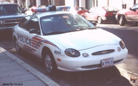 1998 Ford Taurus - White 1998 Ford Taurus police car with "POLICE" text and light bar.