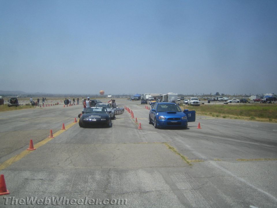 Blue Subaru WRX and black Mazda Miata at a race track event