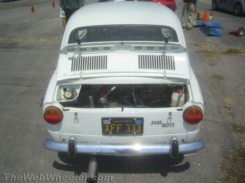 1985 Ford Mustang - Rear view of a white Fiat 850, trunk open, revealing the engine compartment.