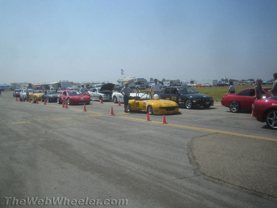 Yellow convertible race car with number 19 on side, parked on asphalt track