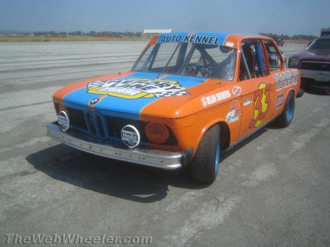 1985 Ford Mustang - This heavily modified race car, possibly a BMW 2002, is seen at an event with "Auto Kennel" branding.