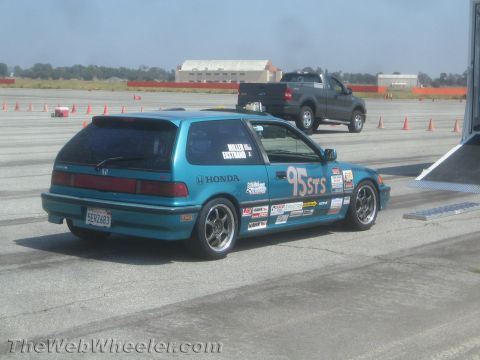1985 Ford Mustang - Teal Honda hatchback, likely a 1990 model, seen at a race track with various sponsor decals.