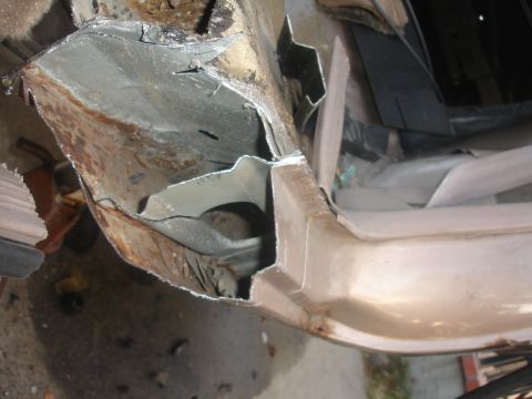 1991 Ford Taurus - Close-up view of a severely damaged and rusted car body panel, showing exposed metal and structural damage.