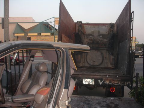1991 Ford Taurus - Damaged car interior visible next to the open bed of a dump truck.