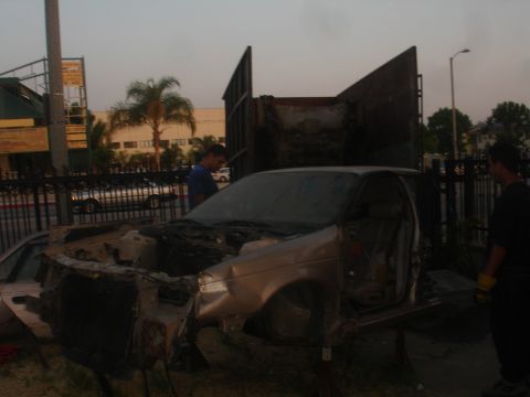 1991 Ford Taurus - A car is being dismantled outdoors, with its engine compartment exposed and parts removed.