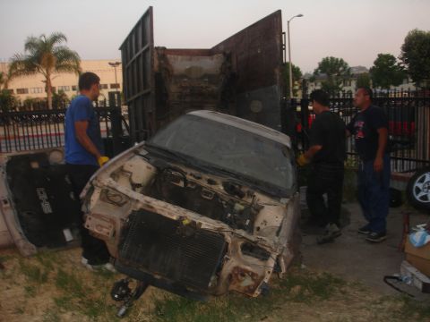 1991 Ford Taurus - A wrecked 1991 Ford Taurus SHO is being loaded into a truck, its front end heavily damaged.