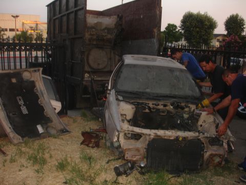 1991 Ford Taurus - A damaged car is being examined by several men next to a large truck, with its hood open.