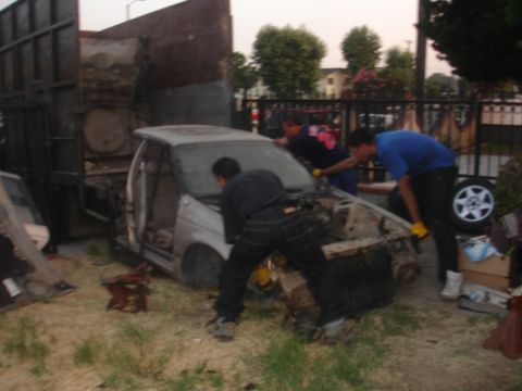 1991 Ford Taurus - Four individuals are dismantling the front end of a silver sedan.