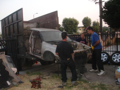 1991 Ford Taurus - A 1991 Ford Taurus is being loaded onto a flatbed truck, with three men standing nearby.
