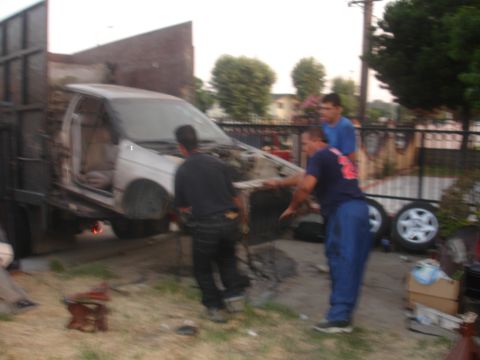 1991 Ford Taurus - Three men are working to load a 1991 Ford Taurus onto a flatbed truck.
