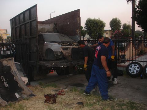 1991 Ford Taurus - A damaged car is being loaded onto a flatbed truck by several men.