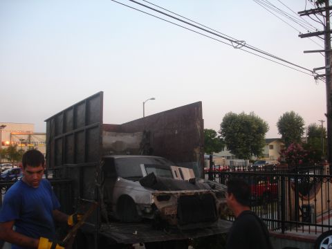 1991 Ford Taurus - A heavily damaged car is being loaded into the back of a large truck.