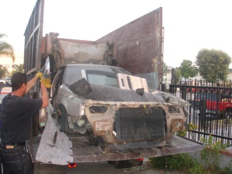 1991 Ford Taurus - A heavily damaged 1991 Ford Taurus is being loaded onto a flatbed truck for transport.
