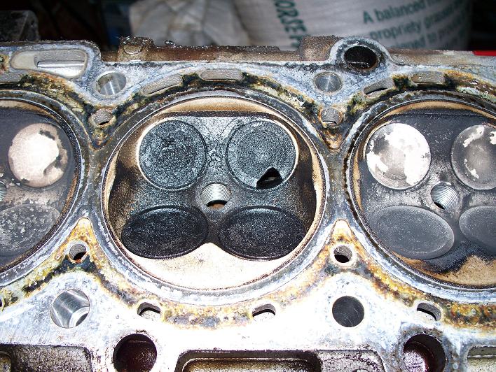 Corroded cylinder head with carbon-caked combustion chambers and valves