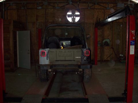 1978 Jeep CJ5 - Rear view of a Jeep CJ-5, identified by its body style and "4 wheel drive" badge, positioned on a lift in a garage.