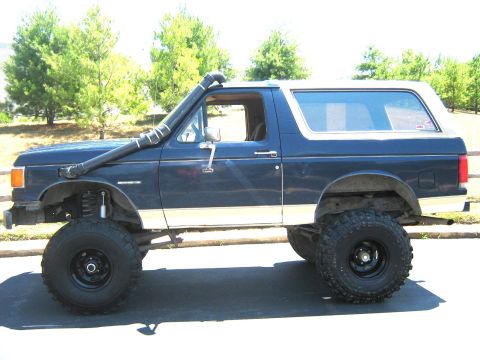 1990 Ford Bronco - This lifted Ford Bronco features a snorkel and off-road tires, modified for terrain.