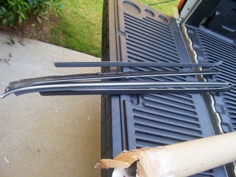 1979 Chevrolet Camaro - Several car trim pieces are laid out on the textured surface of a truck bed.