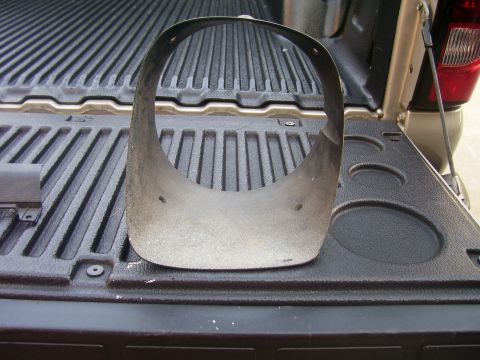 1979 Chevrolet Camaro - This is a headlight bezel, likely from a classic car, shown resting in the bed of a pickup truck.