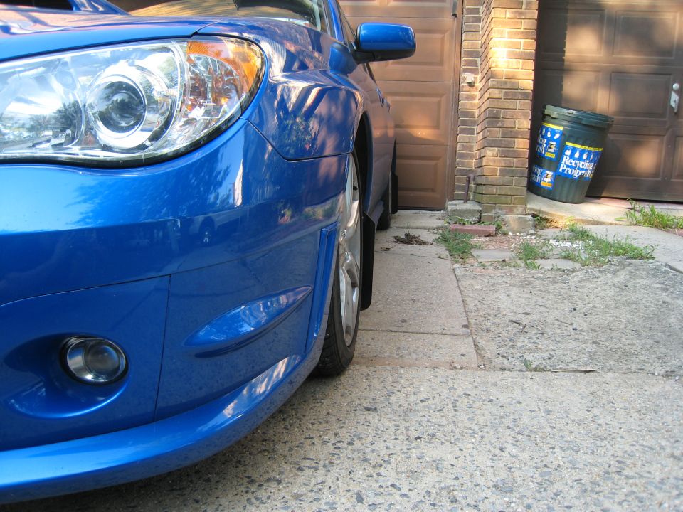 Front bumper and headlight of a blue 2007 Subaru Impreza parked in a driveway
