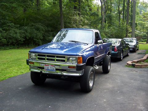 1986 Toyota Hilux - A blue pickup truck is parked in a driveway with two other cars behind it.