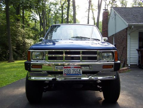 1986 Toyota Hilux - A blue pickup truck is parked in a driveway in front of a house with trees in the background.