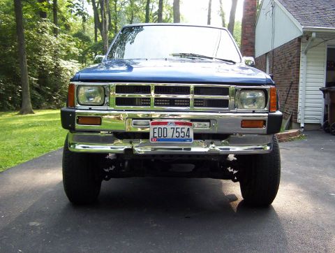 1986 Toyota Hilux - Frontal view of a blue Toyota pickup truck with a chrome bumper and a visible license plate.