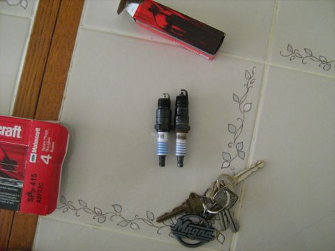 1988 Mercury Grand Marquis - Spark plugs and keys are laid out on a tiled surface next to a Motorcraft box.
