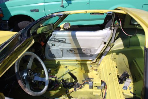 1979 Chevrolet Corvette - Interior view of a yellow 1979 Chevrolet Corvette, with the driver's door open, revealing the dashboard and steering wheel.