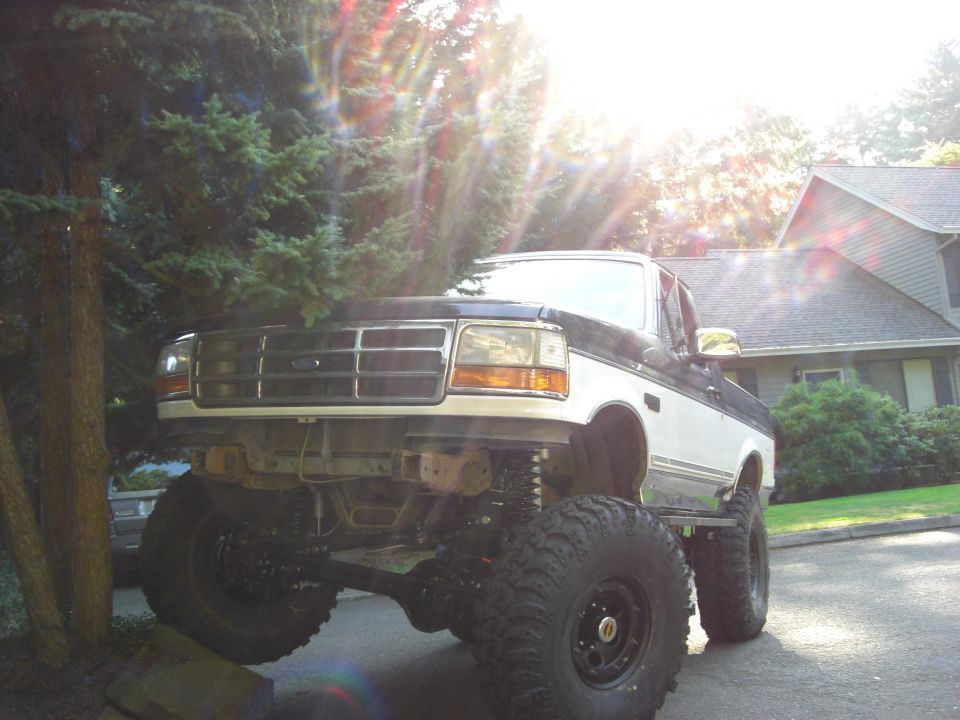 Lifted Ford truck with large tires, parked in a driveway